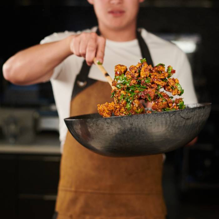 Picture of a chef cooking with a wok on open flame